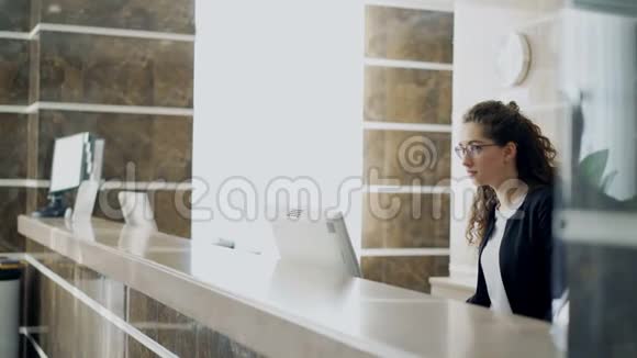 商务客人与前台小姐交谈站在酒店前台用信用卡付账视频的预览图