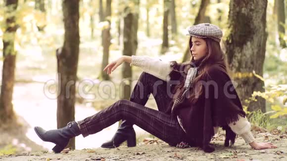 阳光明媚的秋日公园里快乐的年轻女子秋天的女人美丽的黑发少女坐在秋天落叶上视频的预览图