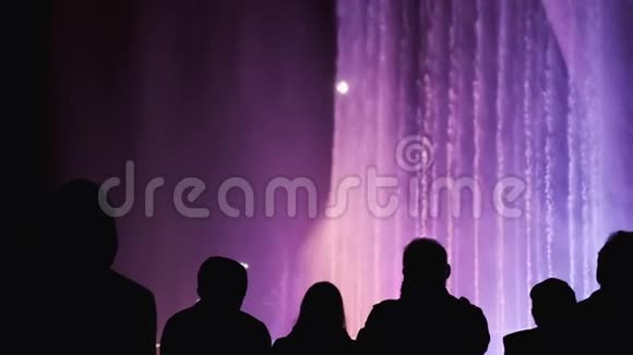 人们的剪影在光节期间五颜六色的喷泉欣赏城市夜景的人群视频的预览图