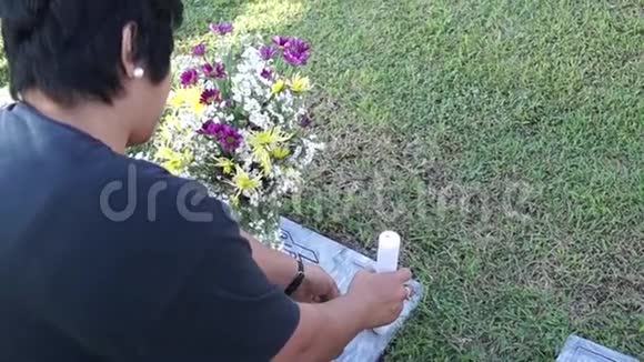 妇女在墓地参观墓碑献蜡烛视频的预览图