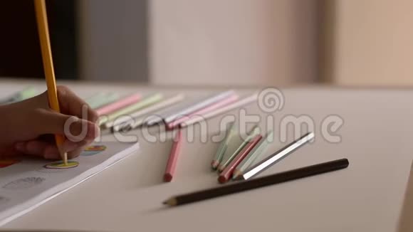 小女孩正在用彩色铅笔在一本书里给图片着色视频的预览图
