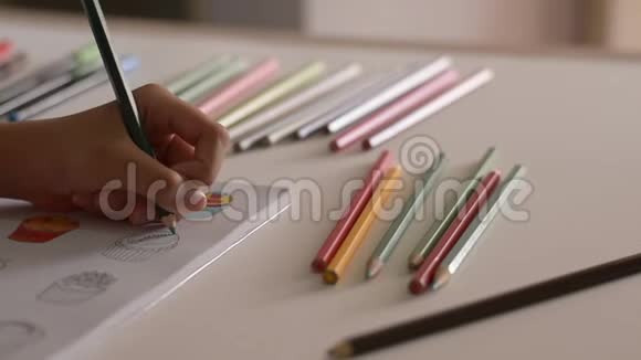 小女孩正在用彩色铅笔在一本书里给图片着色视频的预览图