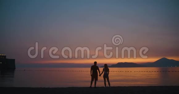 夕阳下的爱情故事在岸边站着的时候男人和女人彼此温柔地接吻视频的预览图