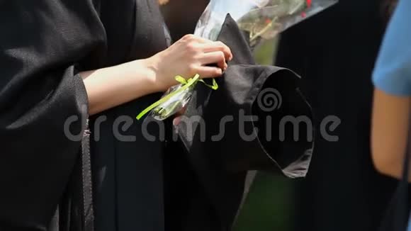 女大学毕业生手持学术帽和一束鲜花视频的预览图
