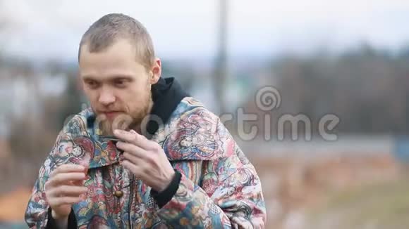 年轻男子穿着复古的玻璃大衣留着胡须在乡村的兰斯凯特上辛勤地演奏着自强不息的音乐视频的预览图