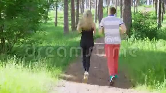 在绿色森林中奔跑的男人和女人的背影视频的预览图