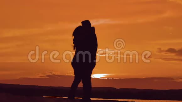 一对相爱的情侣在夕阳下拥抱剪影家庭爱情概念爱一对男女的爱情剪影视频的预览图
