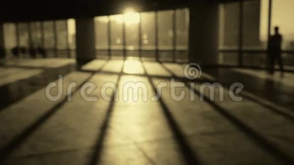 背景模糊的人走在商务大厦内的平台日落光线通过窗口视频的预览图