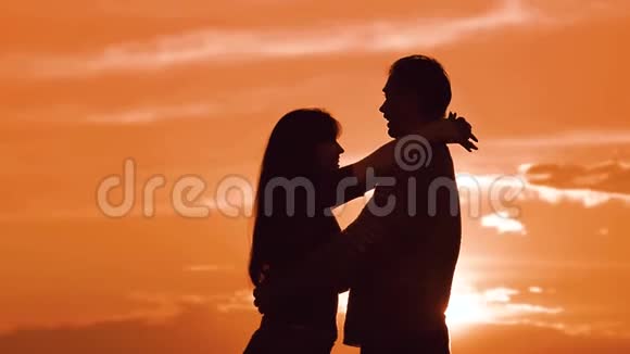 一对相爱的情侣在夕阳下拥抱剪影家庭爱情概念爱一对男女的爱情剪影视频的预览图