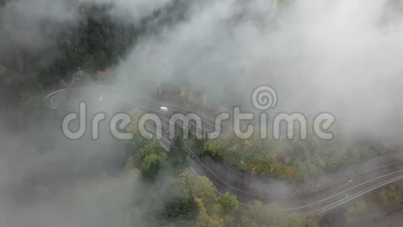 秋天街道从一片雾蒙蒙的森林中空中的景色带着雾和树木在云层中飞舞视频的预览图