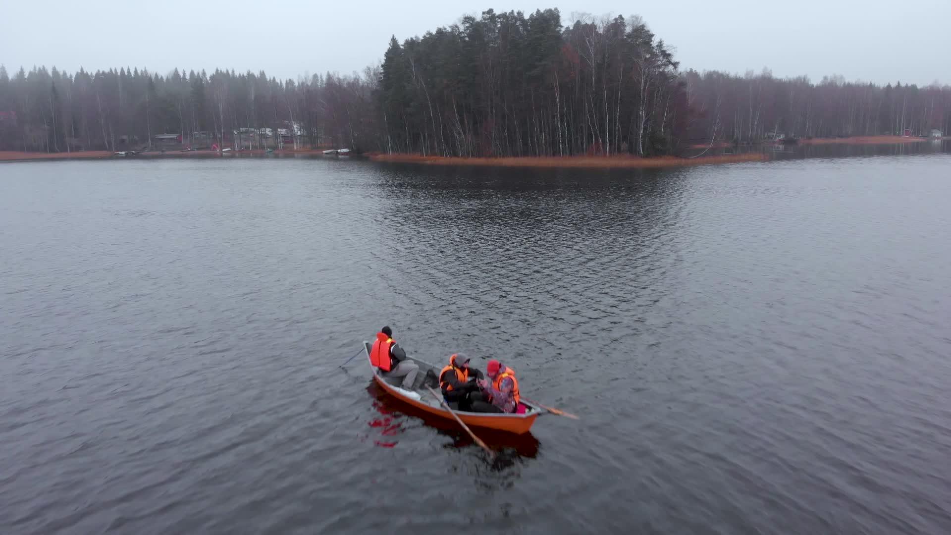 在芬兰湖上与三名男子一起飞行的橙色渔船视频的预览图