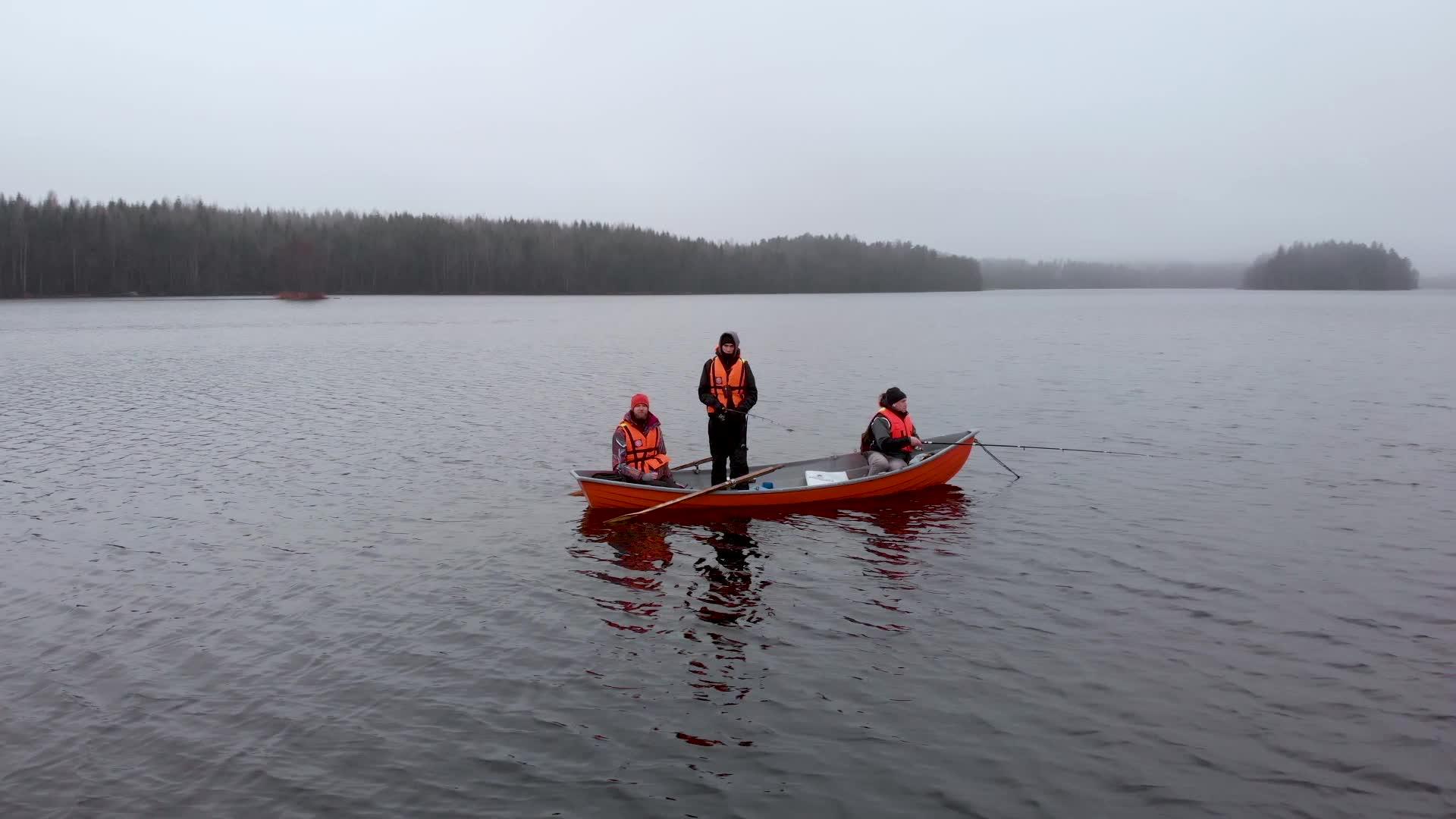 三名男子乘坐橙色船只在芬兰轨道湖上捕鱼视频的预览图