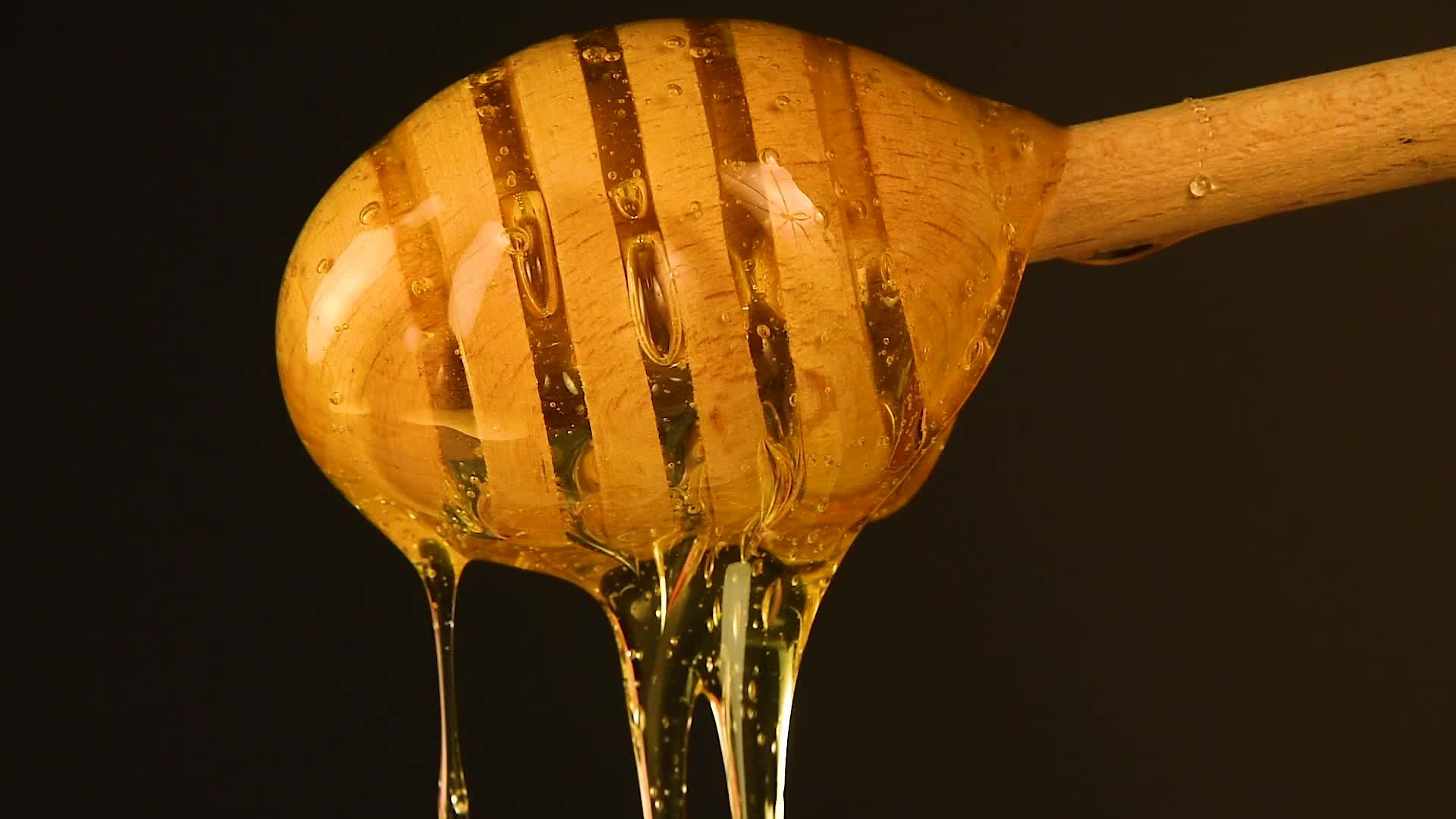 封闭的蜂蜜从黑色木黄色的花朵中流出视频的预览图