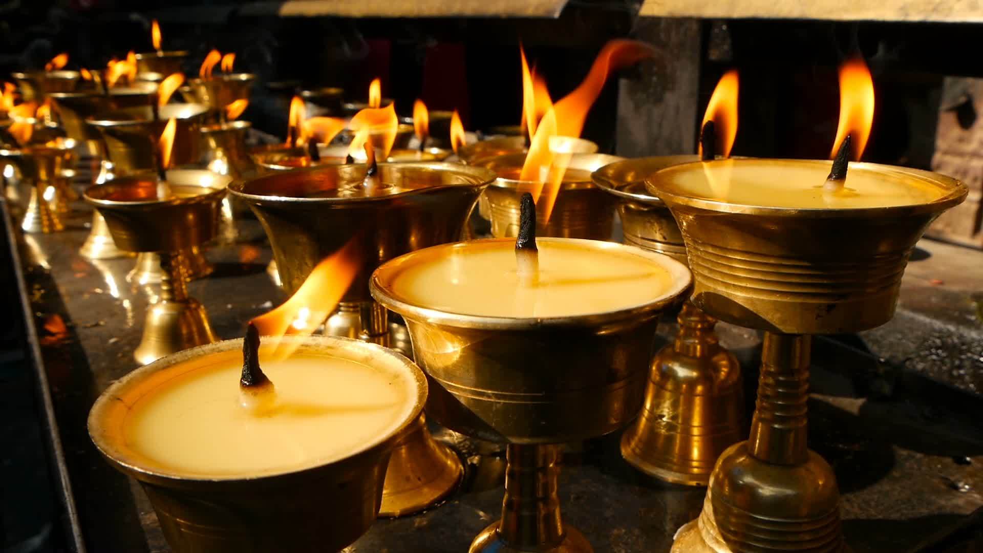 在寺庙里烧蜡烛 看到金色的碗和燃烧的油蜡视频的预览图