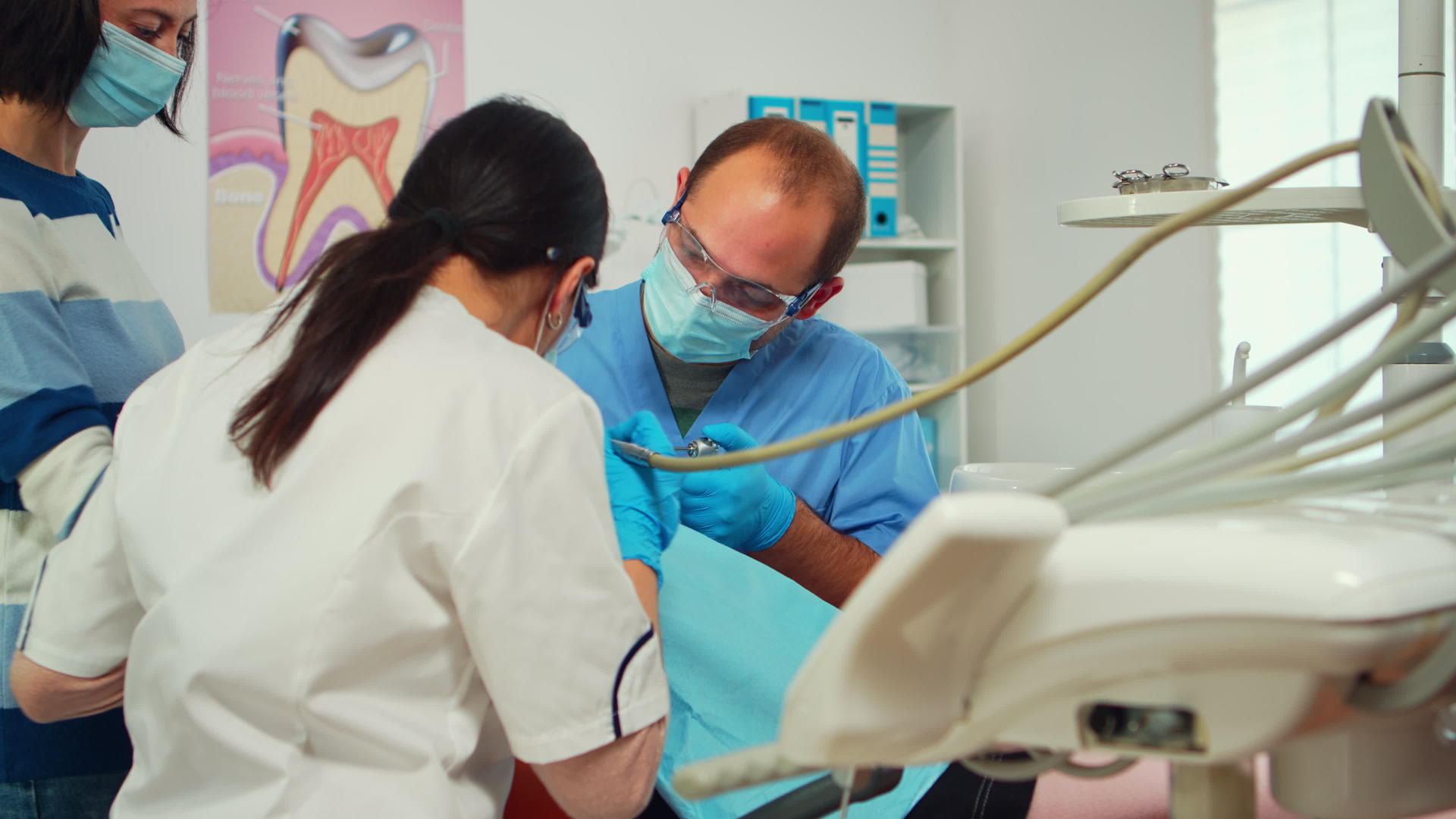 戴着口罩和手套的口腔医生用钻头工具清洁孩子的牙齿视频的预览图