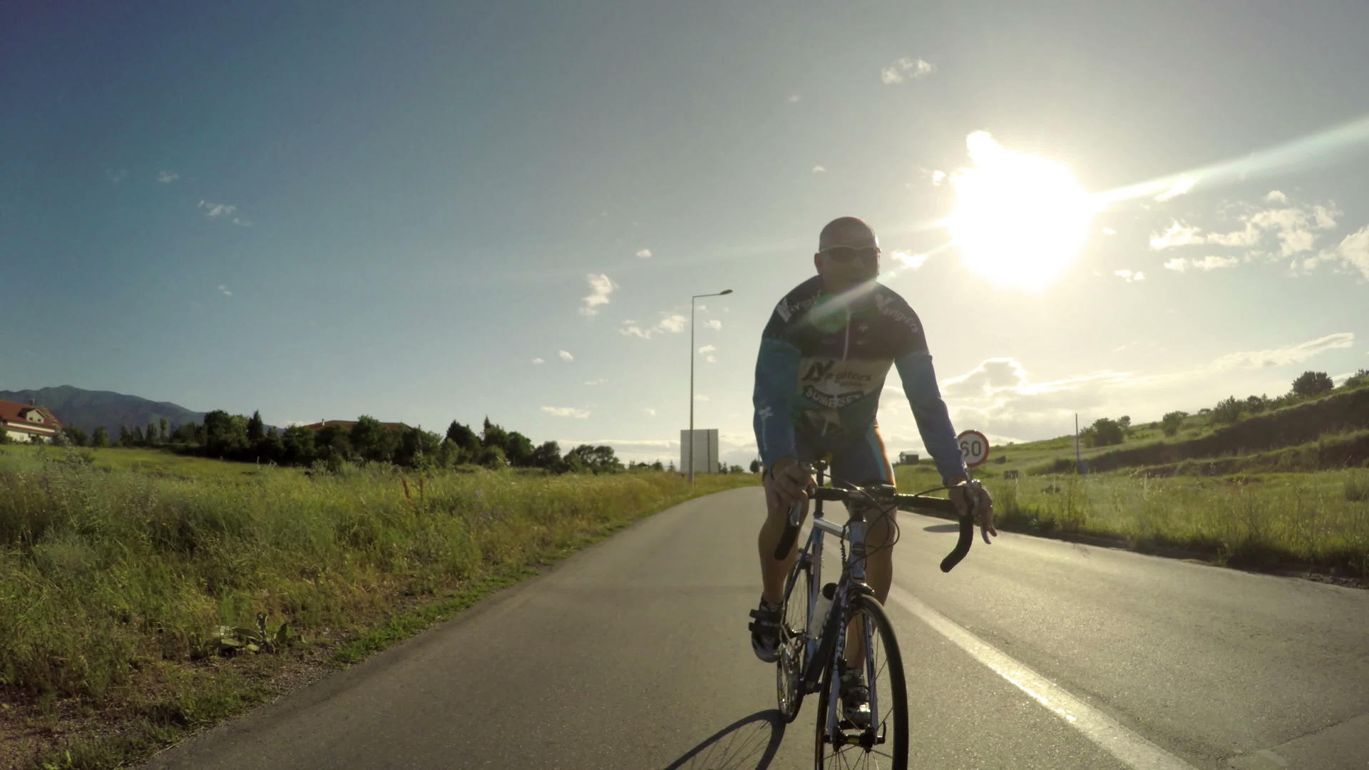 骑自行车的人在路边运动中尽力在山上赛跑 背景是日落 视频的预览图
