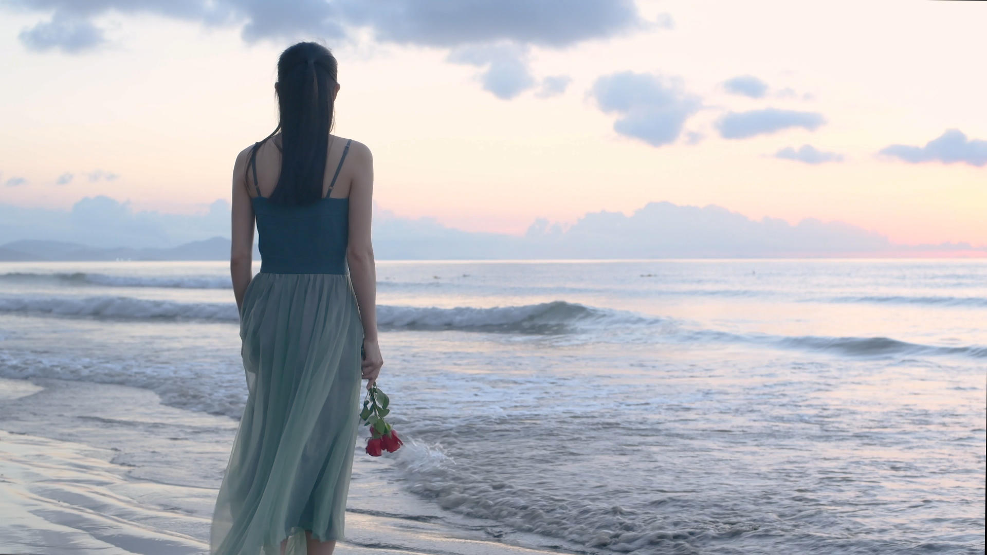 4K少女手持玫瑰花站在日出的海滩上视频的预览图