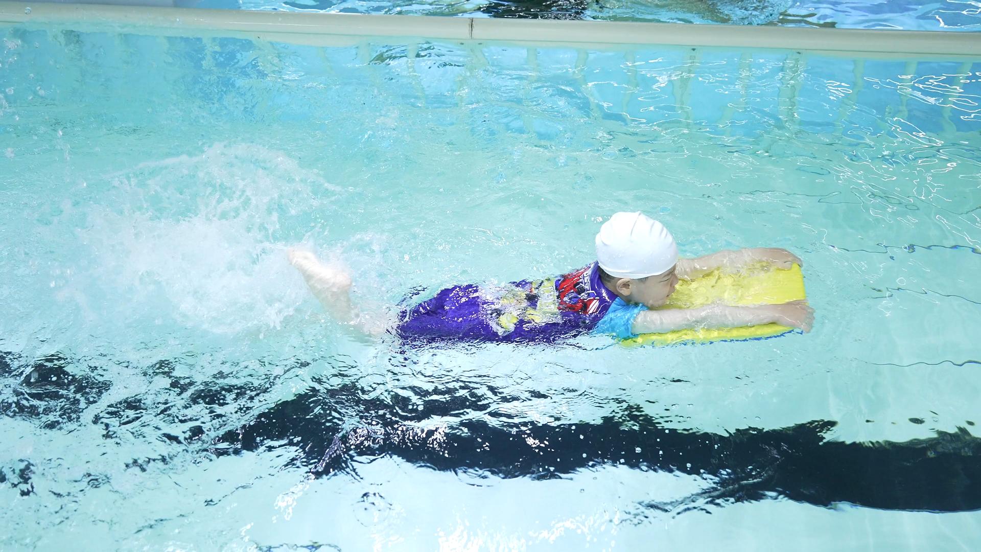 4K游泳课借助滑板练习游泳的小男孩视频的预览图