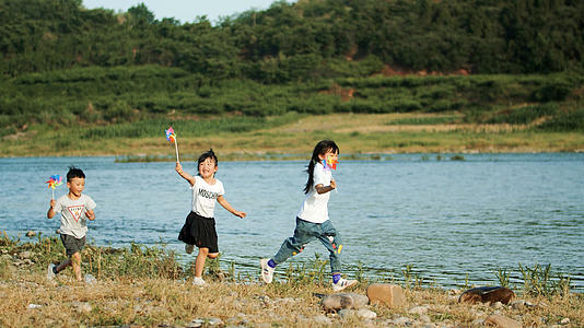 4k实拍三个小朋友小溪边风车奔跑玩耍升格视频的预览图