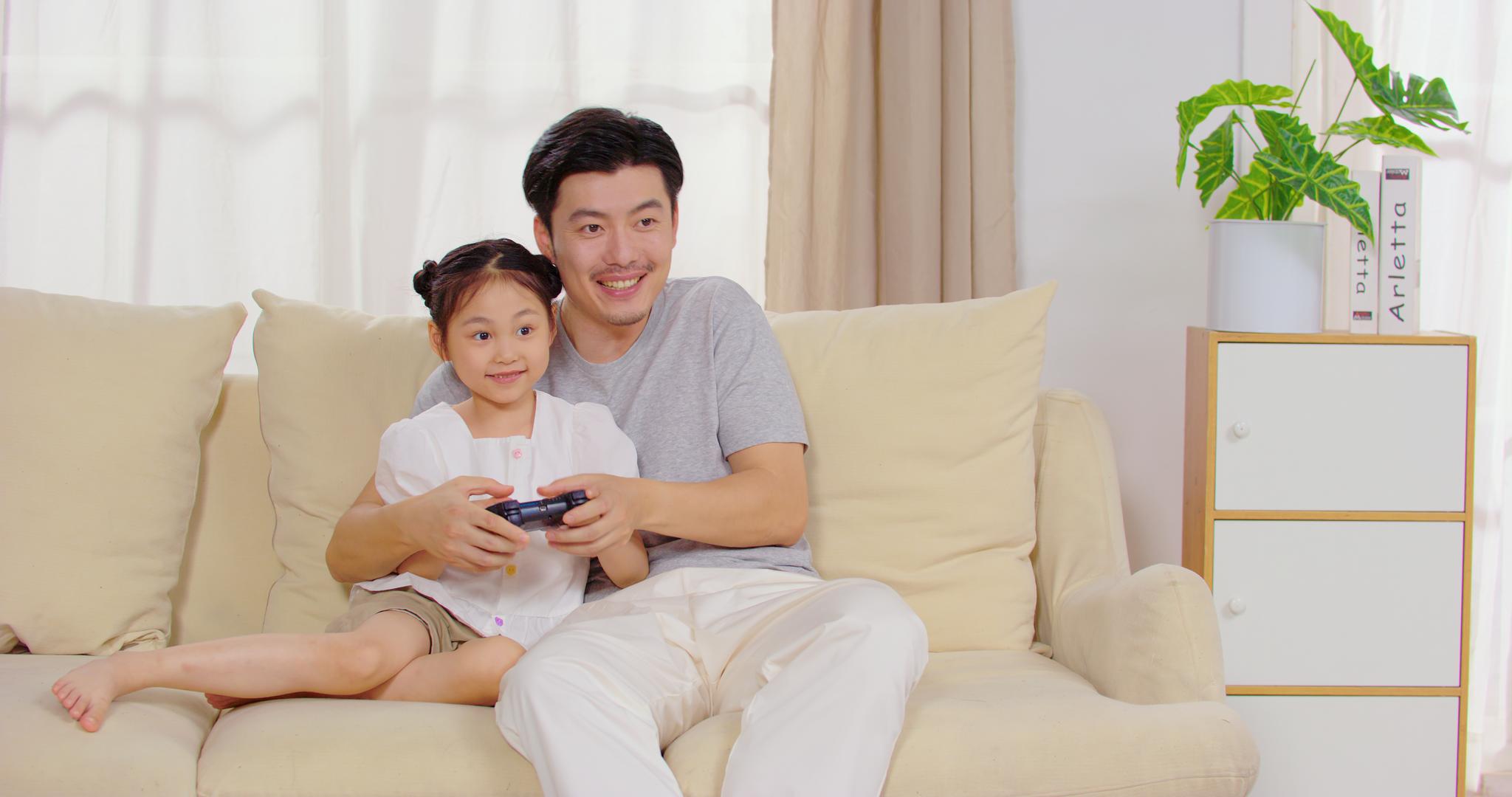 8K爸爸陪女儿坐在沙发上玩游戏视频的预览图