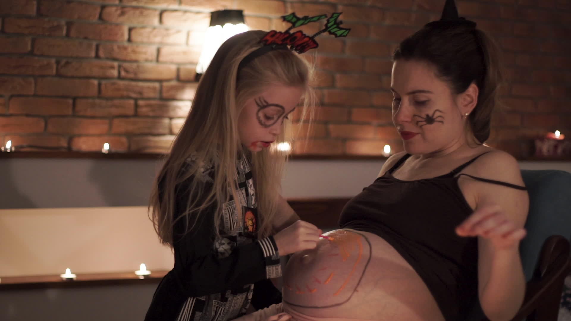 在一个神圣的夜晚 女孩在孕妇的肚子上涂上了油漆南瓜视频的预览图