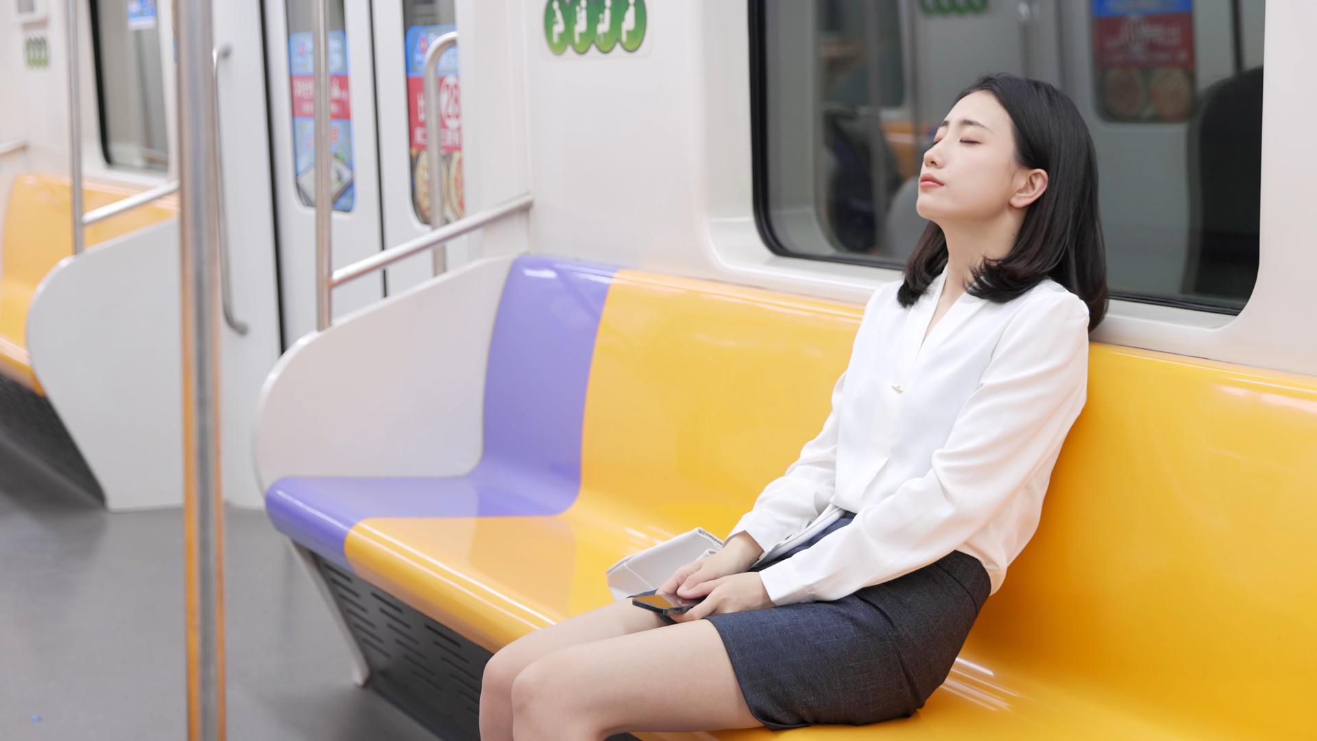 女孩坐地铁玩手机累后闭眼休息视频的预览图