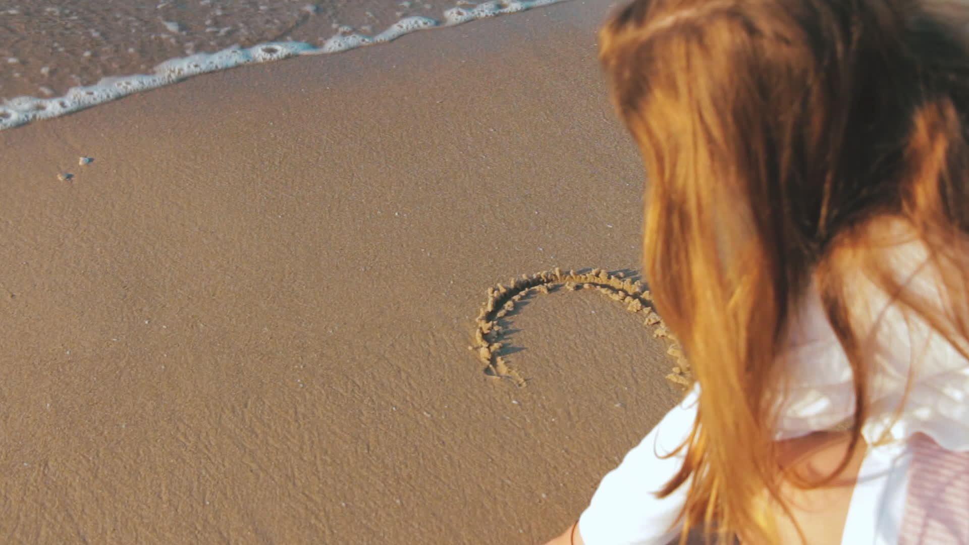 在奇怪的日落时在湿沙上画一个女孩的心形视频的预览图