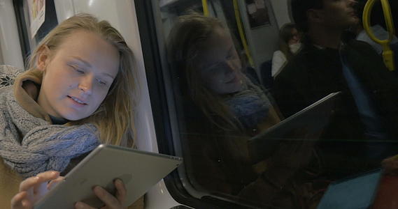 女性在地铁列车上用平板电脑保持联系视频的预览图