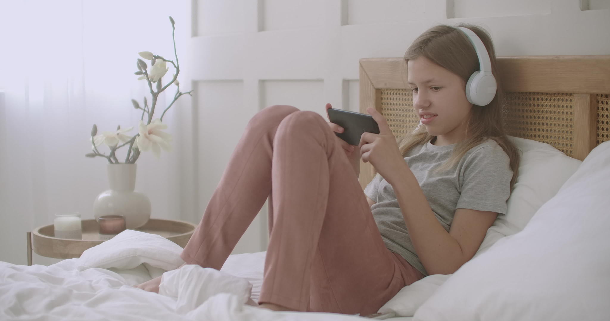 小女孩正在使用智能手机周日早上醒来后在网上玩游戏学习孩子视频的预览图