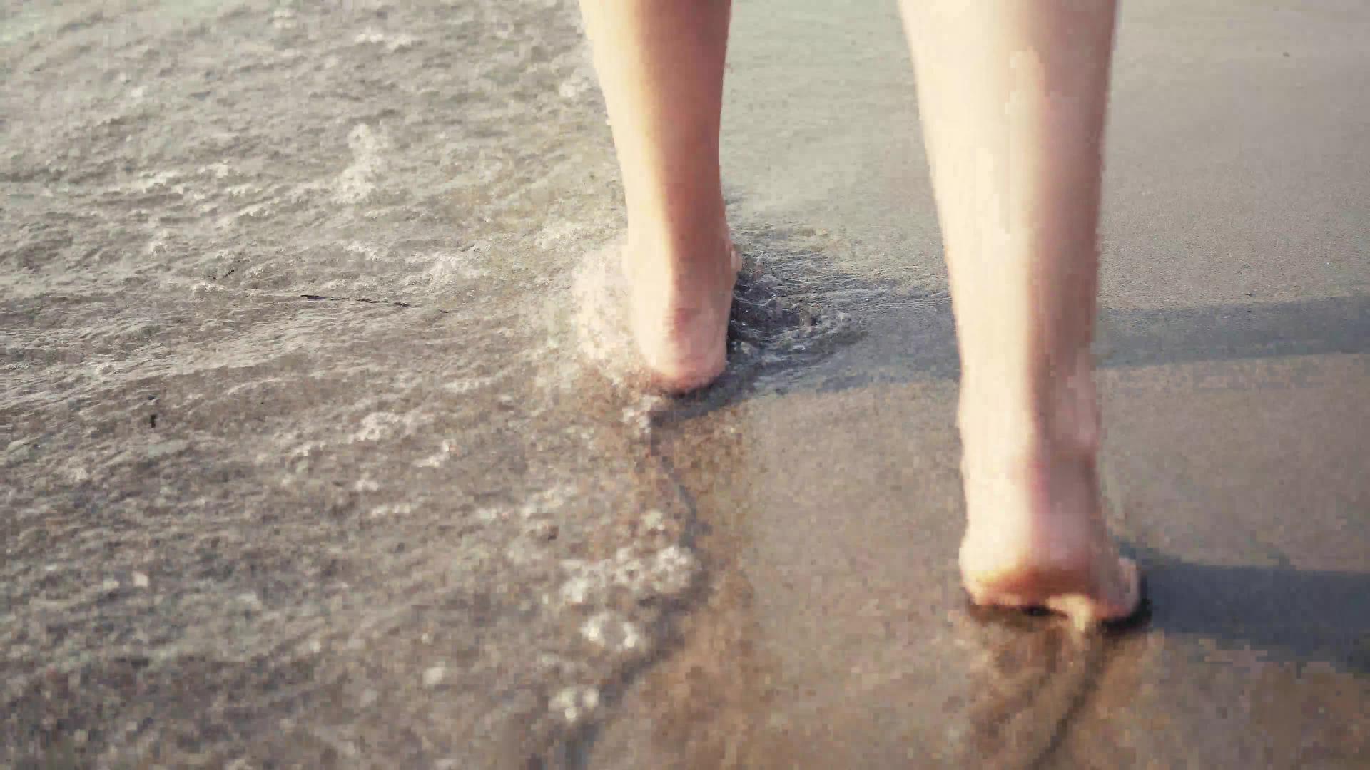 近距离赤脚的女人在海边散步时被海浪冲上了电影制片人视频的预览图