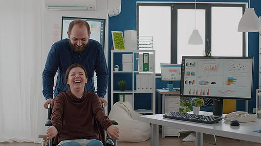 快乐的年轻人和残疾人一起推轮椅他的同事残疾瘫痪视频的预览图