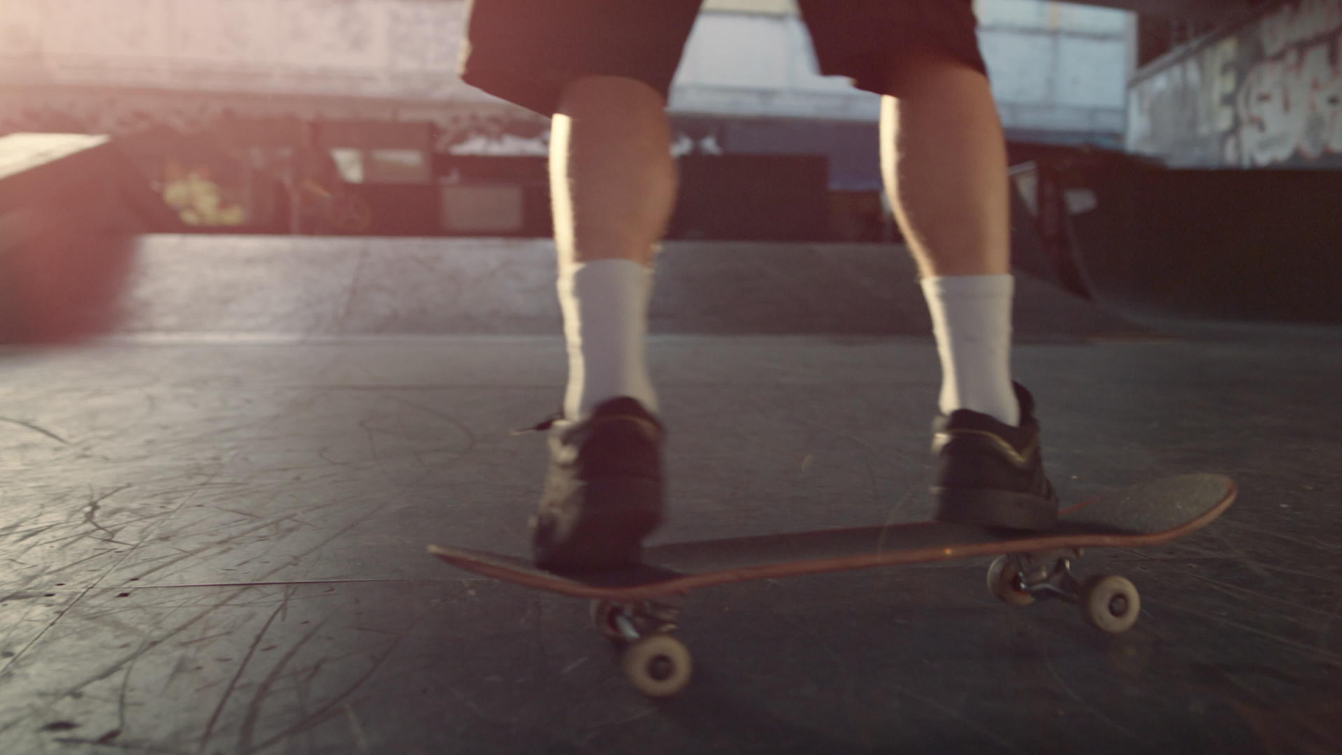 运动型男子在城市滑板公园日落时在滑板上训练技能视频的预览图