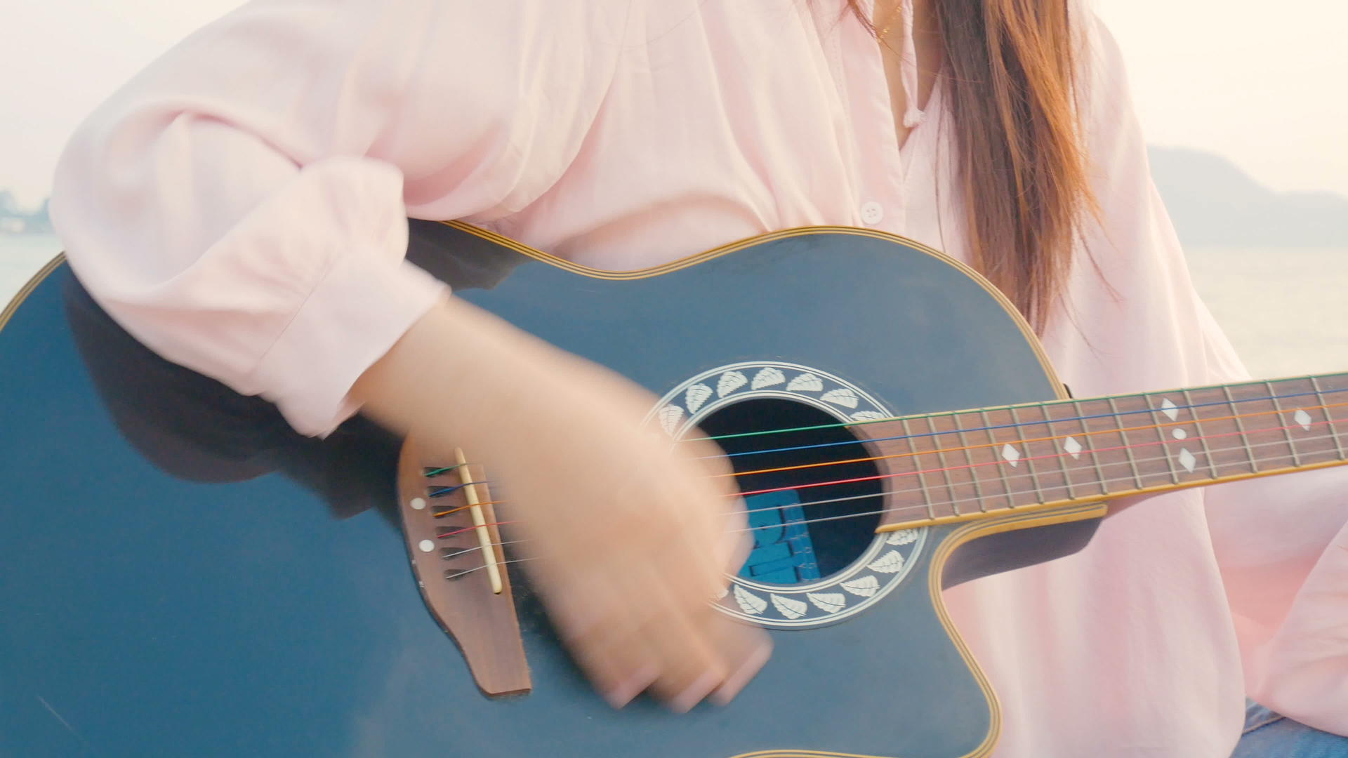 4k关闭长发女孩的长发女孩在海滩上弹奏吉他日落时温柔的感觉视频的预览图