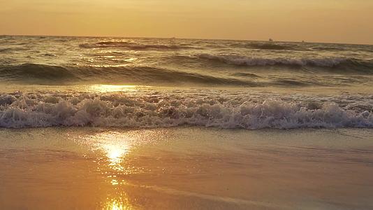 日落时太阳下山沙浪冲向海滩慢慢运动视频的预览图