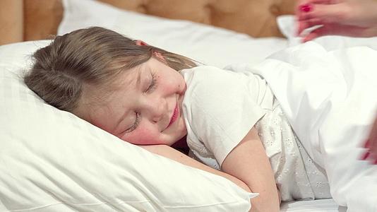 可爱的小女孩应该睡在床上她妈妈拿着毯子睡觉视频的预览图