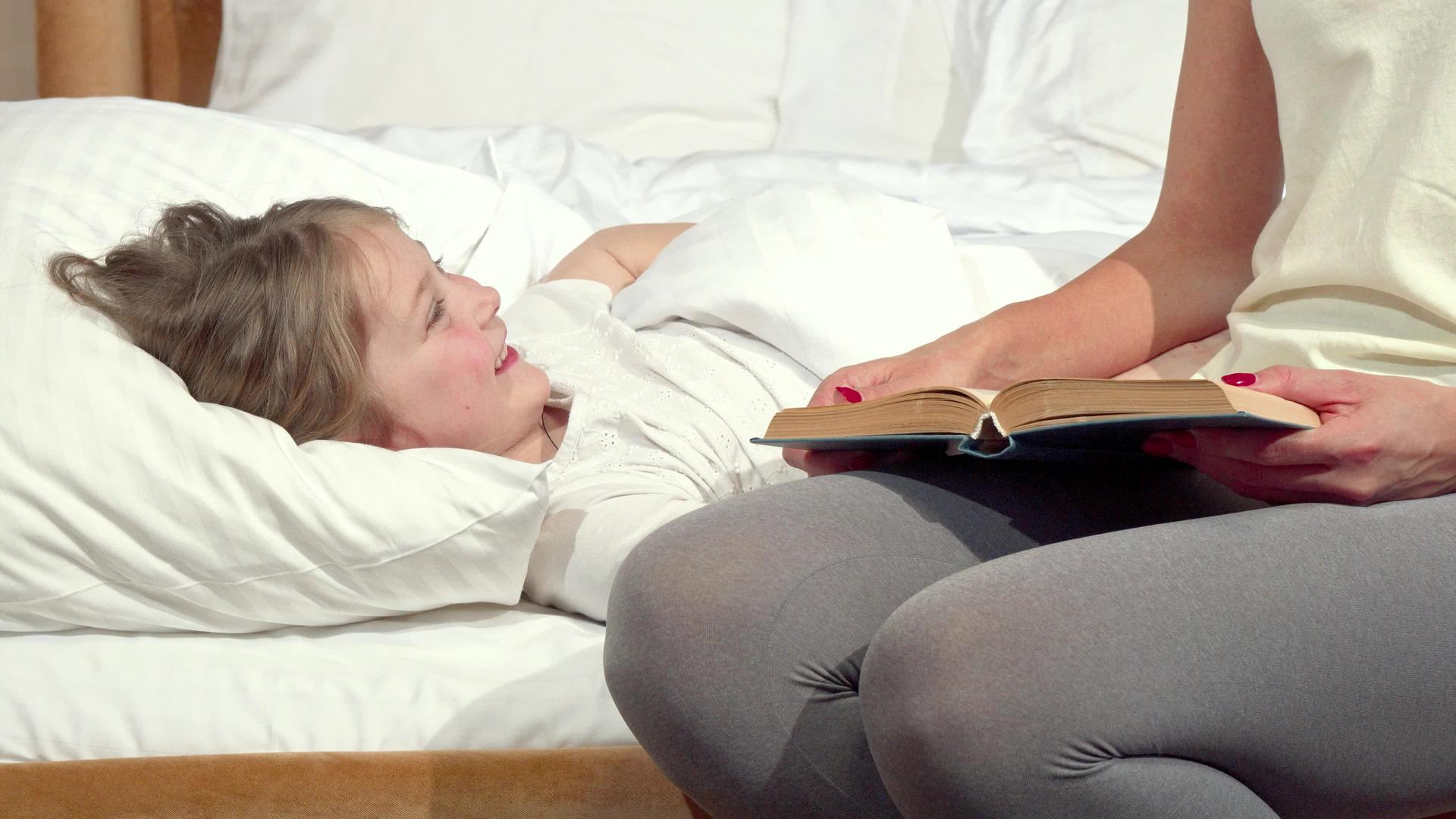 这个可爱的小女孩在床上她妈妈在睡觉前给她看书视频的预览图