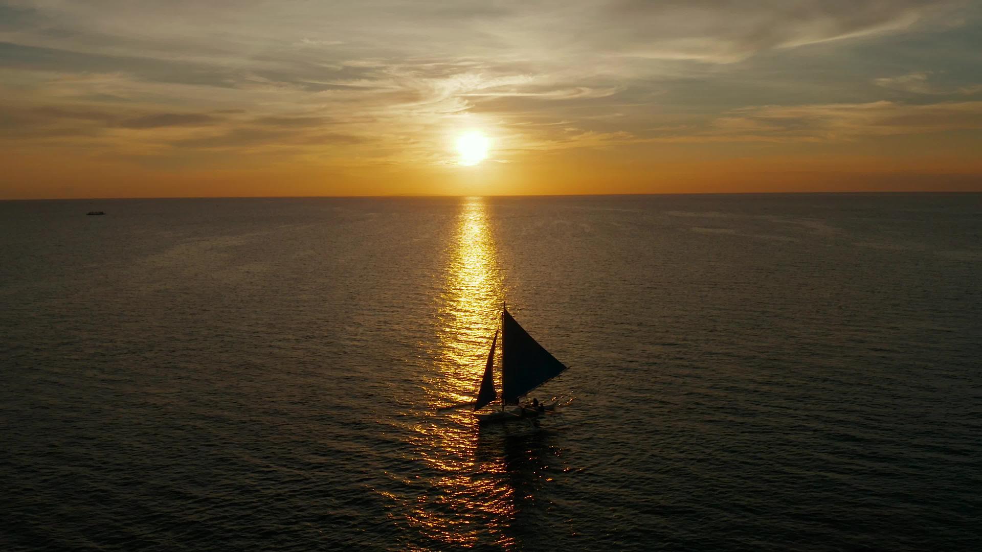日落期间的帆船剪影鸟瞰长滩岛菲律宾水面反射的太阳视频的预览图