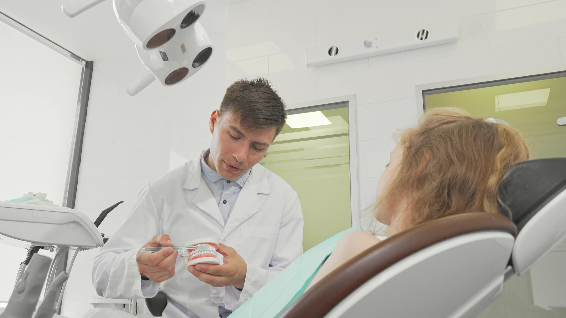 年轻的男性牙医展示了如何在牙科模型上刷牙视频的预览图