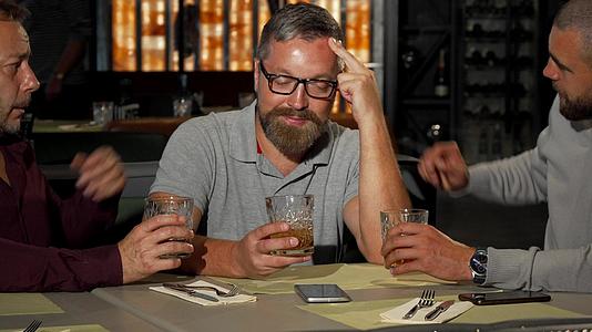 两个成熟的男人在酒吧喝酒时支持他们不愉快的朋友视频的预览图