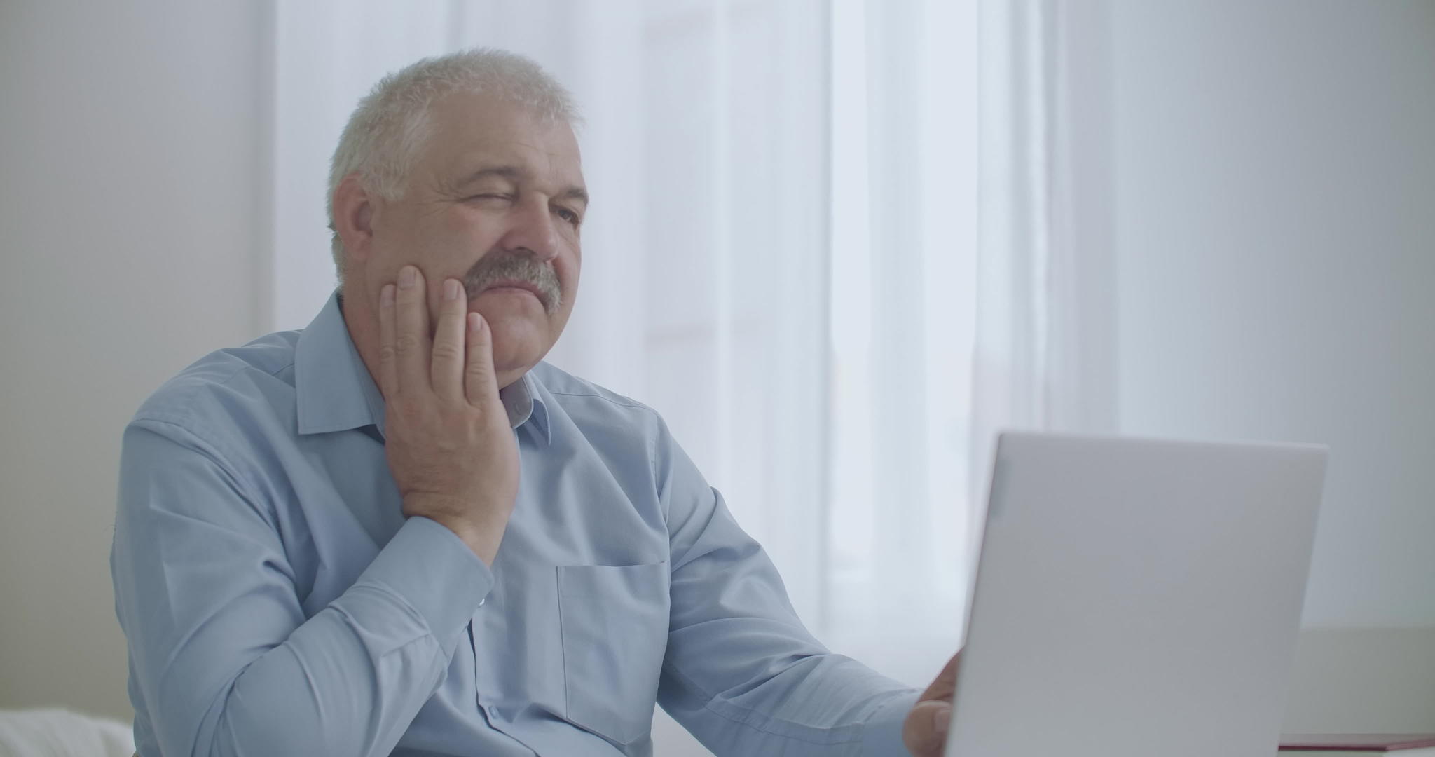 牙痛男子在办公室用笔记本电脑擦脸颊 以缓解牙齿视频的预览图