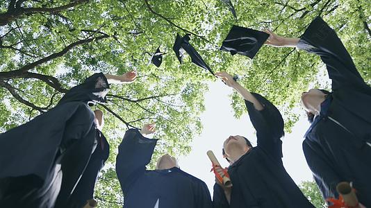 穿着学士服的大学毕业生向天上抛起学士帽视频的预览图