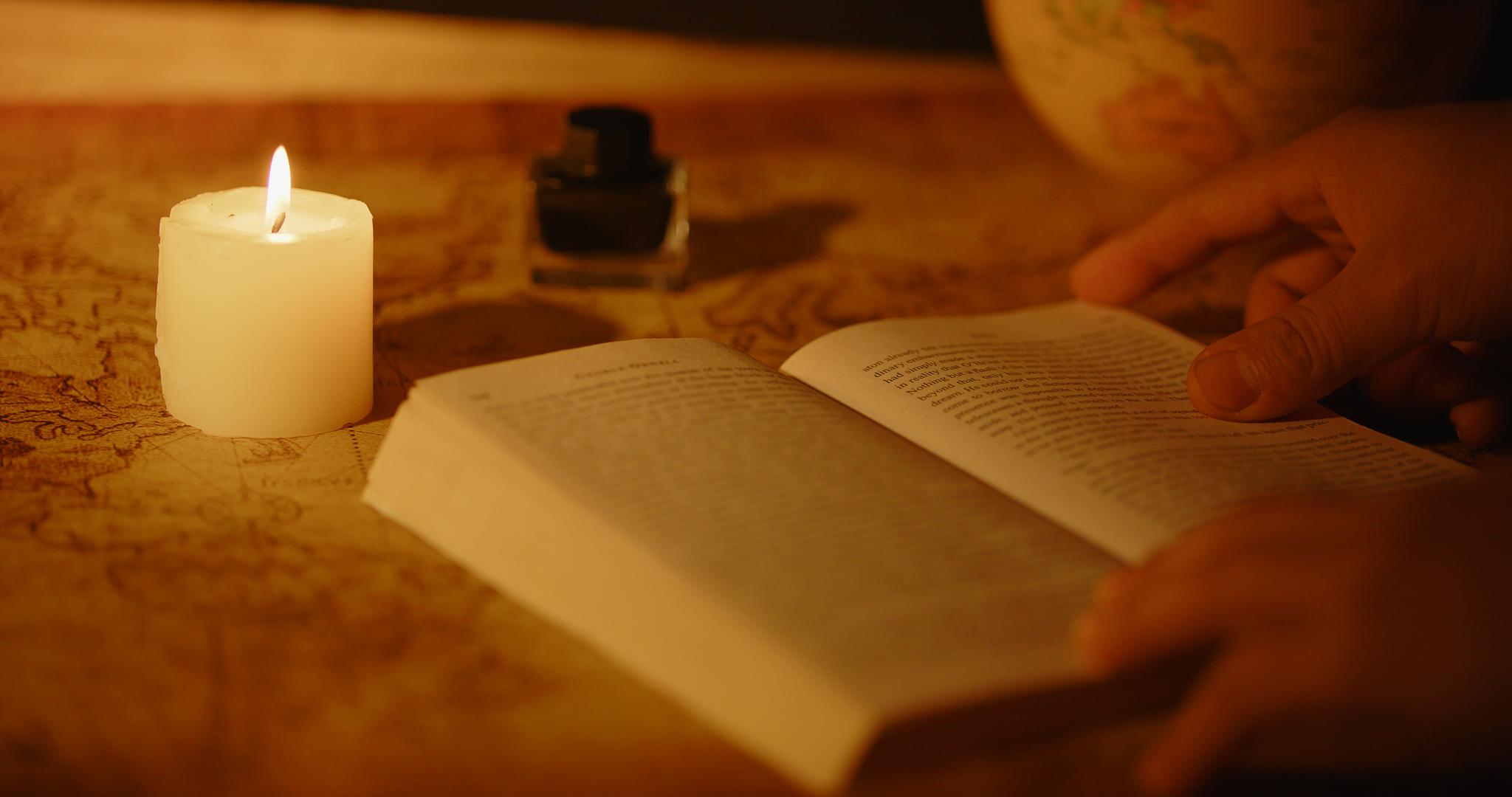 蜡烛照明翻书的手部特写视频的预览图