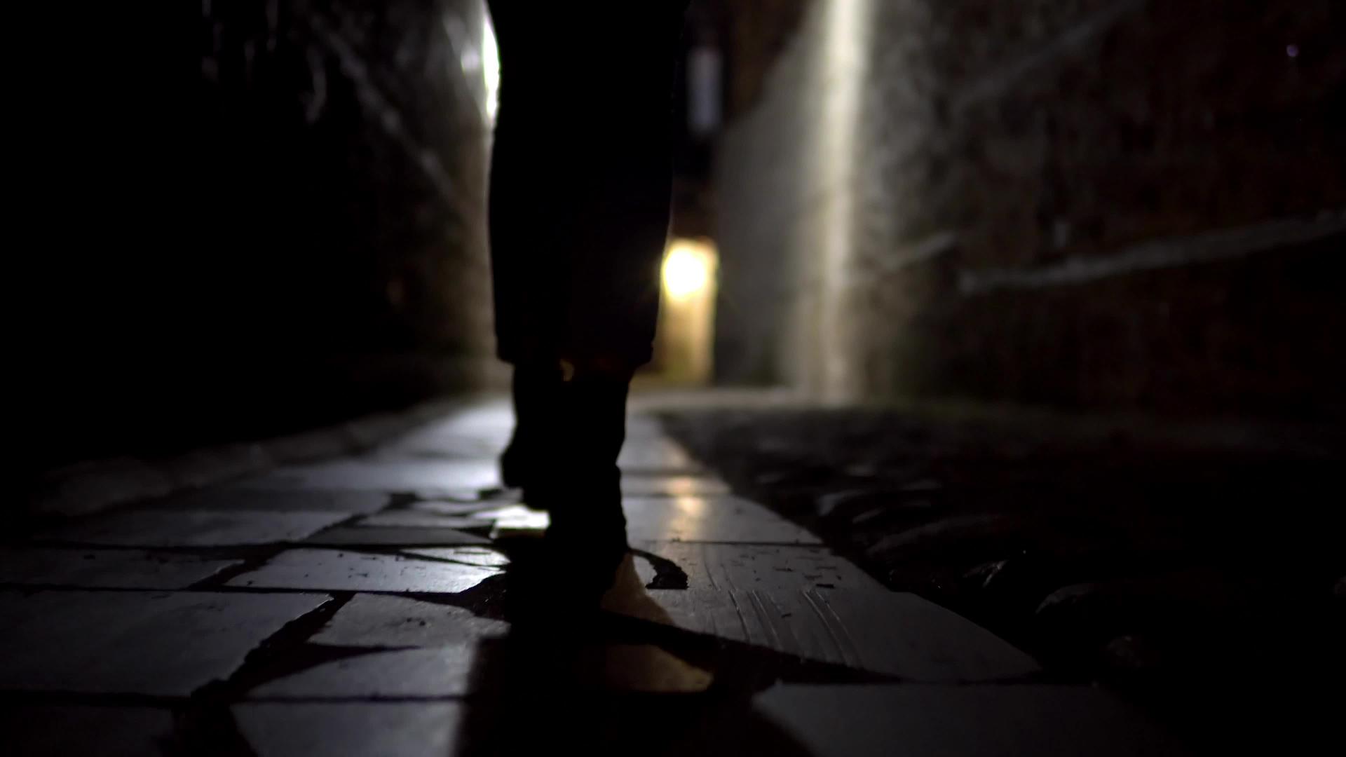 在古老的街道上黑暗的街道上妇女用脚踩着靴子在铺石路上行走视频的预览图