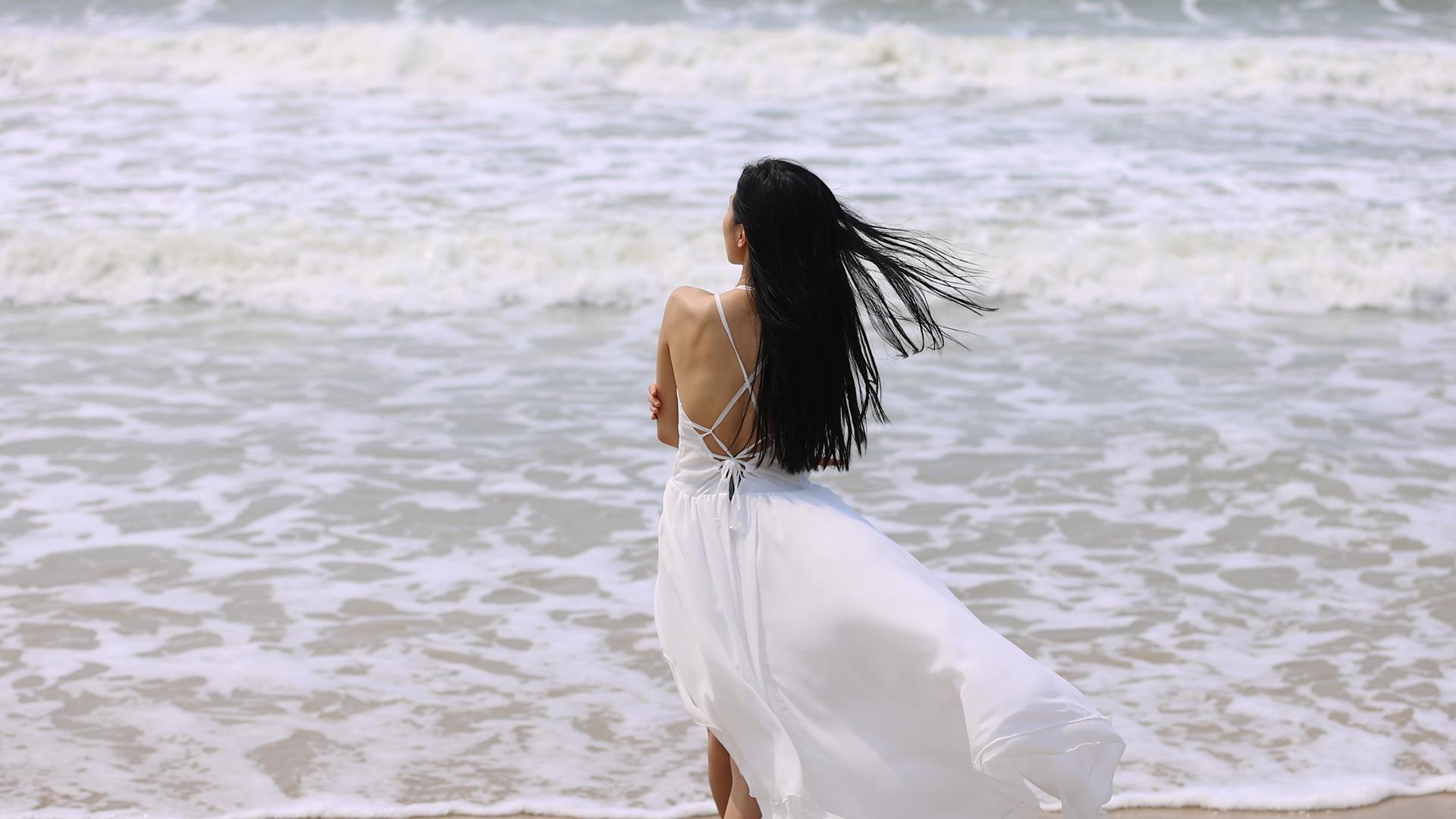 沙滩上优雅的青年美女背影视频的预览图