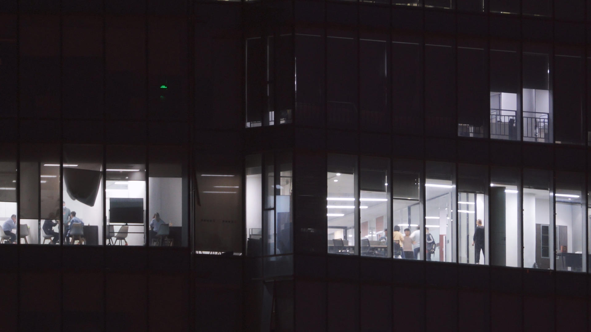 航拍城市夜晚金融互联网公司写字楼灯火通明加班的员工4k素材视频的预览图
