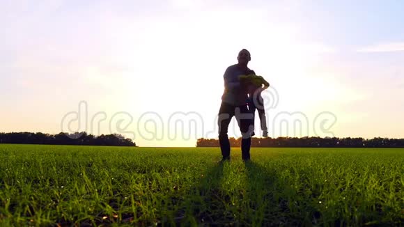 日落时分幸福的家庭在公园里玩大自然父亲把儿子抱在怀里慢慢地转身视频的预览图
