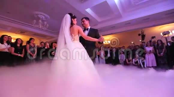 美丽的年轻新婚夫妇跳舞他们的第一支舞蹈被白色的烟雾笼罩在餐厅举行婚礼视频的预览图