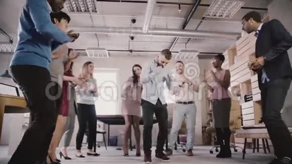年轻的高加索员工与同事跳舞庆祝商务成就在休闲办公室聚会慢动作视频的预览图