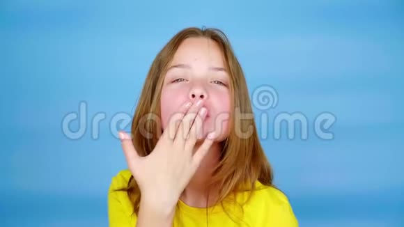 穿着黄色T恤的少女正在看着镜头吹着一个吻露出心形视频的预览图