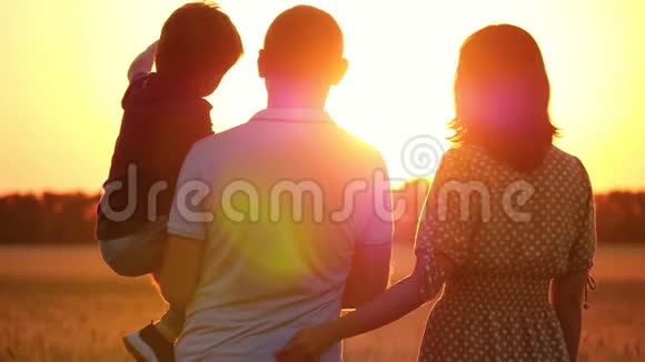 幸福的一家人看着夕阳站在麦田里抱着孩子的男人女人拥抱男人视频的预览图